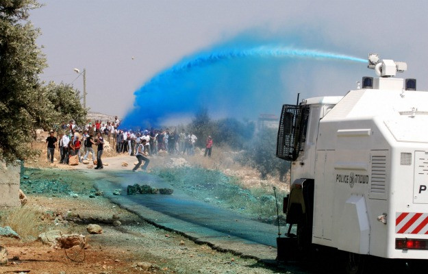 Israeli police water cannon spraying blue dye. Image courtesy of AFP Getty Images and Abbas Momani.