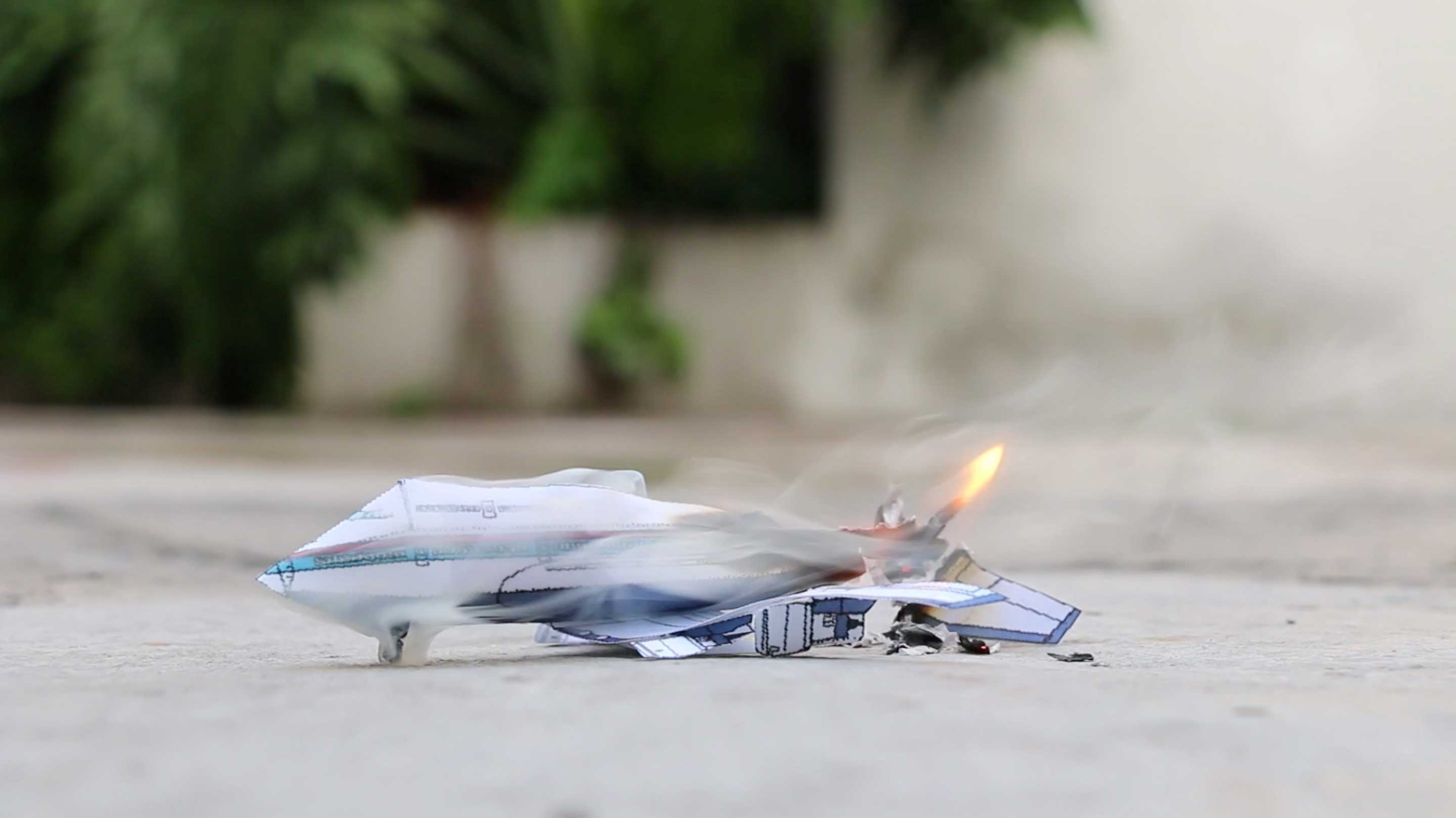 A detailed paper airplane set ablaze, with a small flame at its end.